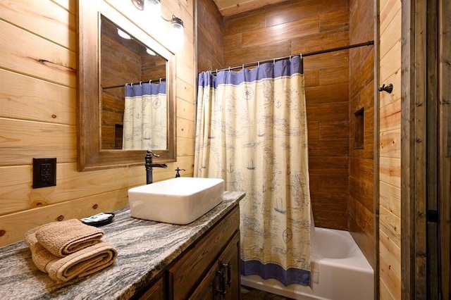 bathroom with vanity, wooden walls, and shower / bath combo with shower curtain