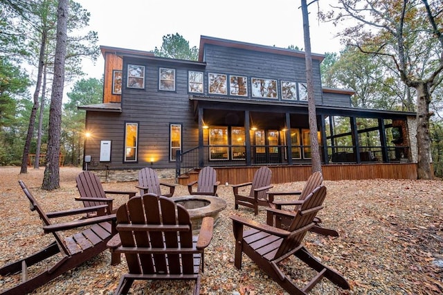 back of property featuring an outdoor fire pit and a sunroom