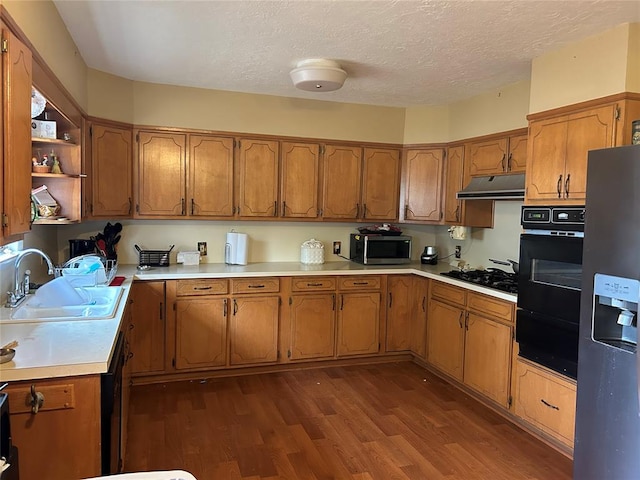 kitchen featuring a textured ceiling, sink, black appliances, and dark hardwood / wood-style floors