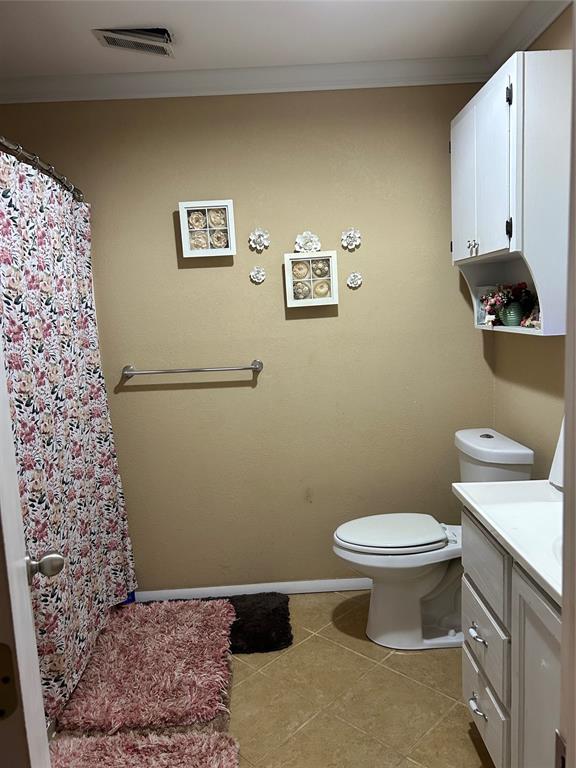 bathroom with crown molding, tile patterned flooring, vanity, and toilet