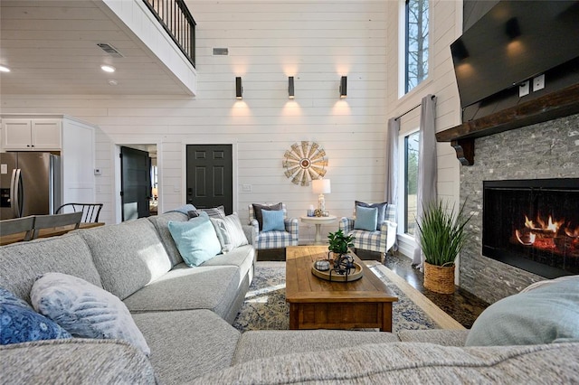 living room with a high ceiling, hardwood / wood-style flooring, wooden walls, and a premium fireplace