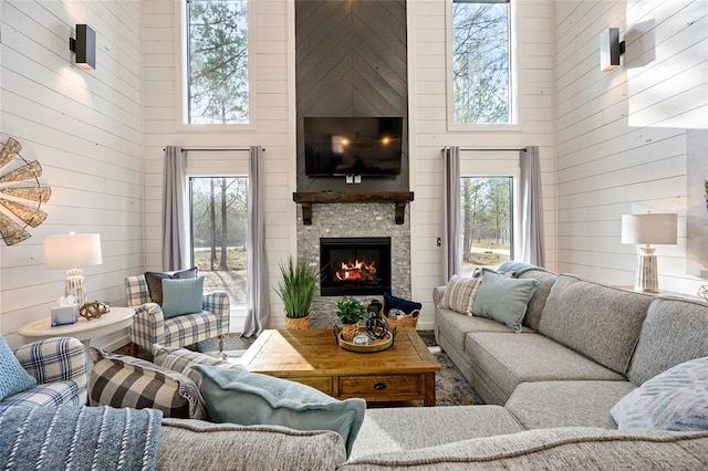 living room featuring a towering ceiling, a healthy amount of sunlight, and wood walls