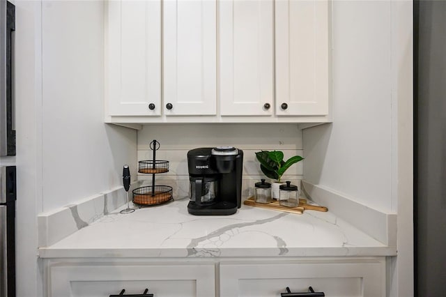 bar with light stone countertops and white cabinets