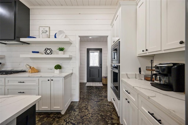 kitchen with light stone countertops, appliances with stainless steel finishes, and white cabinetry