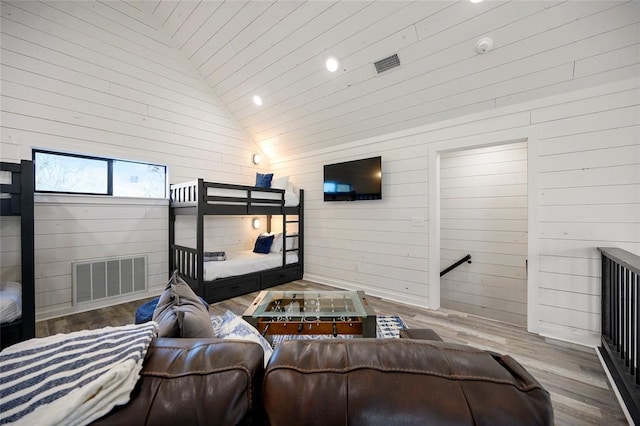 living room with wood-type flooring, high vaulted ceiling, and wooden walls