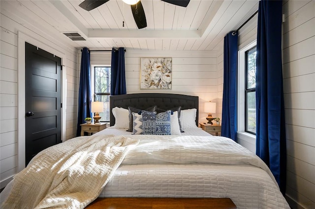 bedroom with multiple windows, ceiling fan, and wood walls