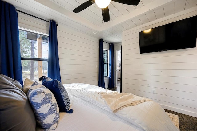 bedroom with beam ceiling, ceiling fan, and wood walls