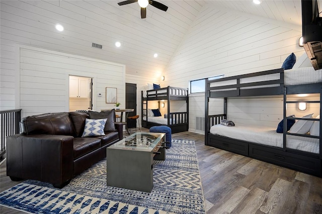 bedroom featuring wooden walls, high vaulted ceiling, ceiling fan, and dark wood-type flooring