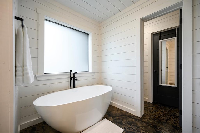 bathroom with a tub to relax in and wooden walls