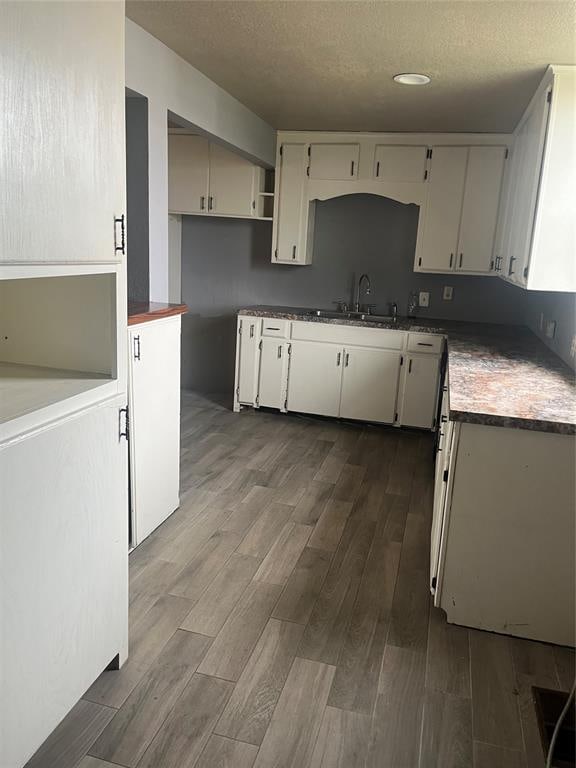 kitchen featuring a textured ceiling, white cabinets, sink, and dark wood-type flooring