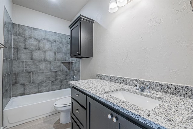 full bathroom featuring hardwood / wood-style floors, vanity, toilet, and tiled shower / bath combo