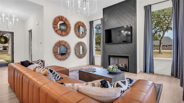 living room with a large fireplace, light hardwood / wood-style flooring, and a chandelier