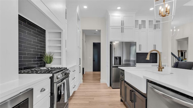 kitchen featuring white cabinets, light hardwood / wood-style flooring, tasteful backsplash, decorative light fixtures, and stainless steel appliances