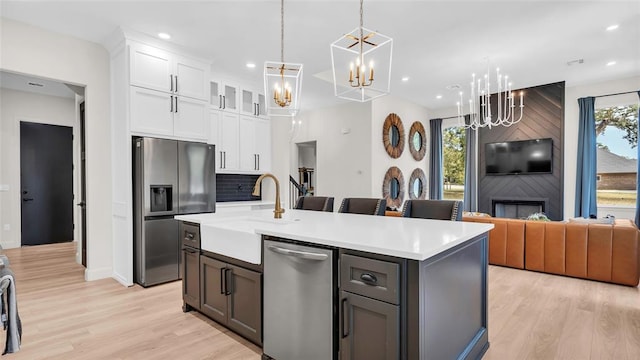 kitchen featuring white cabinetry, stainless steel appliances, decorative backsplash, a kitchen island with sink, and light wood-type flooring