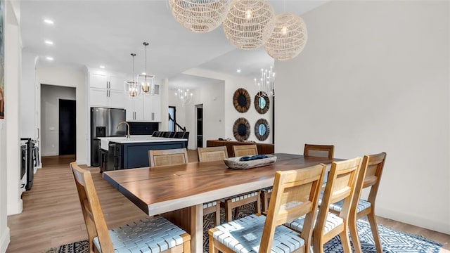 dining space featuring a chandelier, sink, and light hardwood / wood-style floors