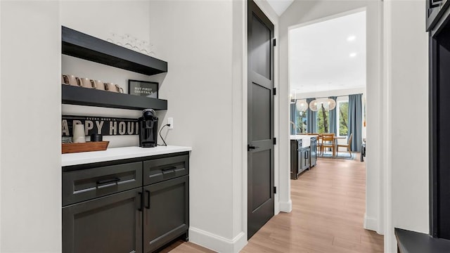 bar with gray cabinetry and light hardwood / wood-style floors