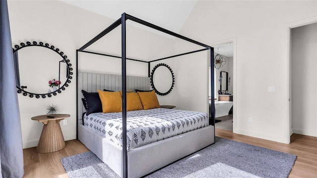 bedroom with hardwood / wood-style flooring, lofted ceiling, and ensuite bathroom