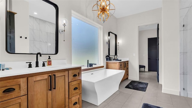 bathroom with tile patterned flooring, vanity, a washtub, and an inviting chandelier