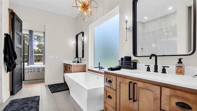 bathroom featuring tile patterned floors, vanity, a washtub, and a chandelier