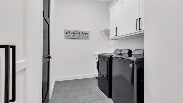 clothes washing area with cabinets, light tile patterned floors, and washing machine and clothes dryer