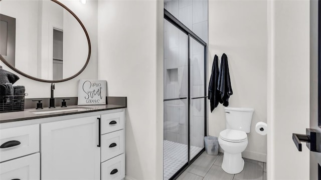 bathroom featuring tile patterned flooring, vanity, toilet, and a shower with shower door