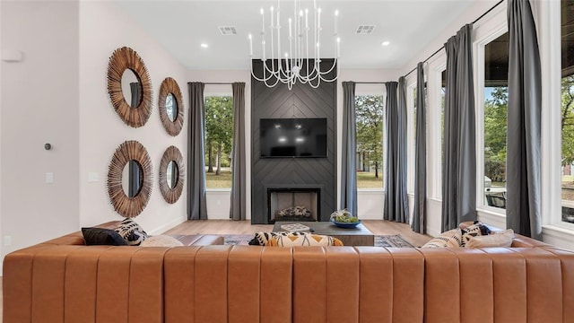 living room featuring a large fireplace, light hardwood / wood-style floors, and an inviting chandelier