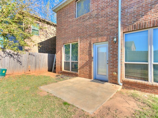 view of exterior entry featuring a yard and a patio