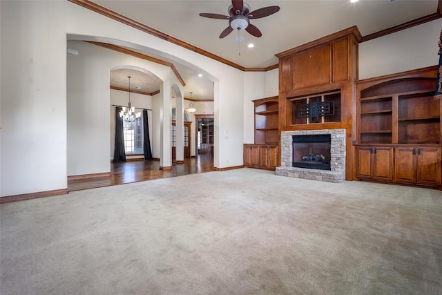 unfurnished living room featuring dark hardwood / wood-style flooring, ceiling fan with notable chandelier, a stone fireplace, and crown molding