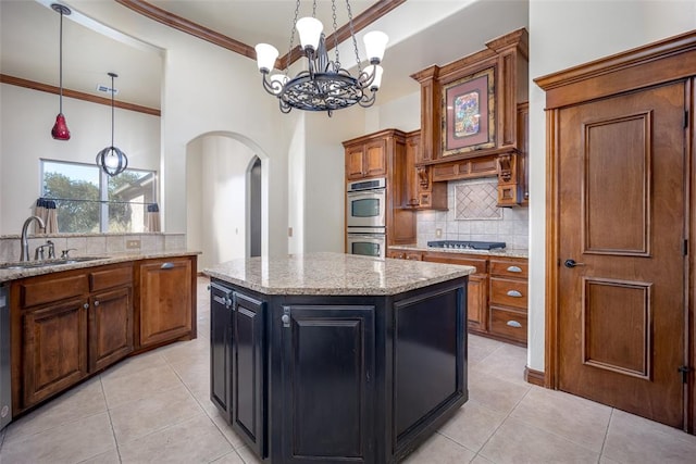 kitchen featuring crown molding, sink, a notable chandelier, a kitchen island, and hanging light fixtures