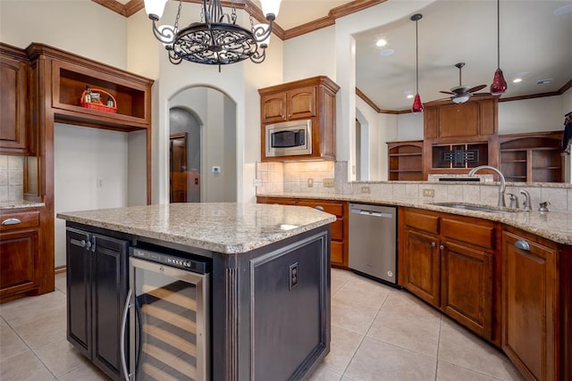 kitchen with stainless steel appliances, ceiling fan, beverage cooler, sink, and a center island