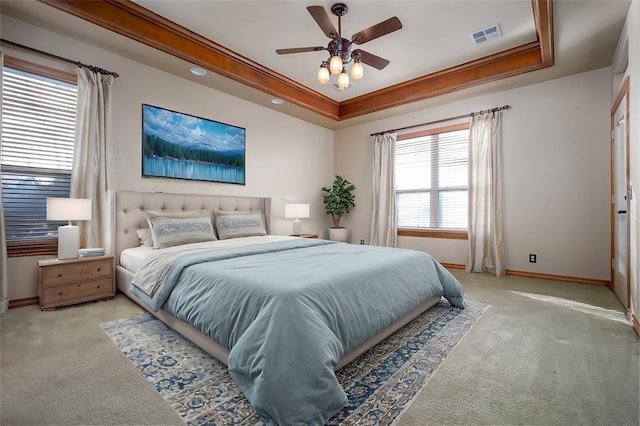 carpeted bedroom with a tray ceiling, ceiling fan, and crown molding