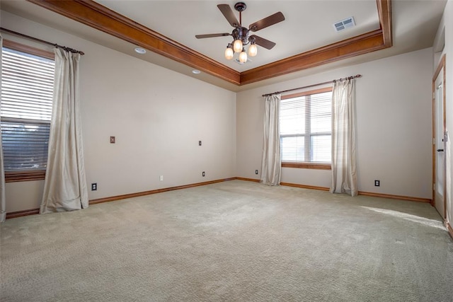 spare room with ceiling fan, a raised ceiling, light colored carpet, and crown molding