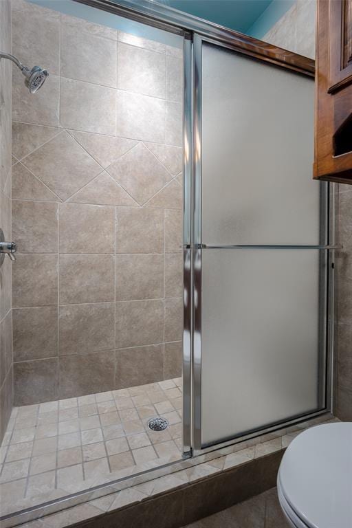 bathroom with a shower with door and toilet