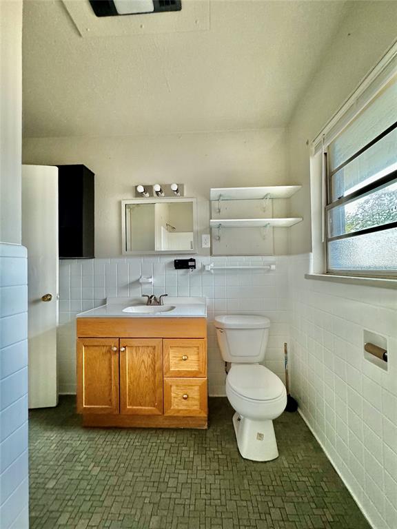 bathroom with vanity, tile walls, and toilet