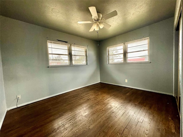 unfurnished room with a textured ceiling, ceiling fan, plenty of natural light, and dark hardwood / wood-style floors