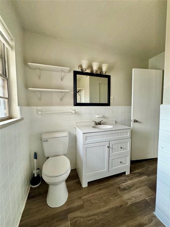 bathroom featuring a textured ceiling, vanity, wood-type flooring, and tile walls