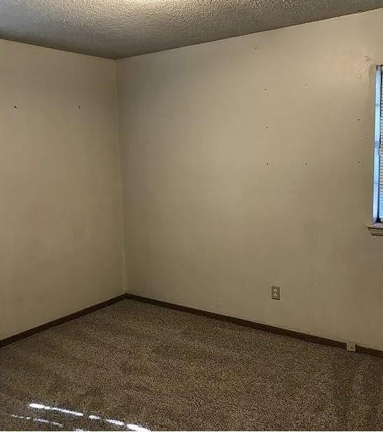 unfurnished room featuring carpet and a textured ceiling