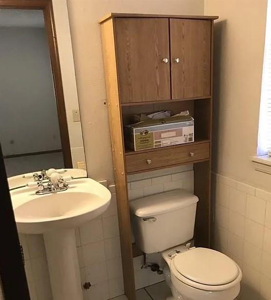 bathroom with tile patterned floors, tile walls, and toilet