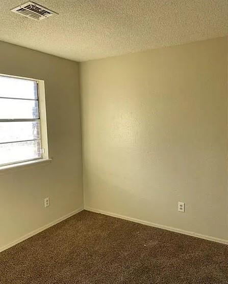 9816 NE 5th St, Midwest City, OK 73130 - spare room featuring dark carpet and a textured ceiling
