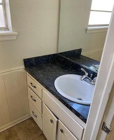 9816 NE 5th St, Midwest City, OK 73130 - bathroom featuring vanity, a wainscoted wall, and a decorative wall
