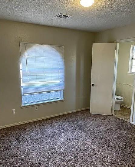 9816 NE 5th St, Midwest City, OK 73130 - unfurnished bedroom with a textured ceiling, carpet, and ensuite bathroom