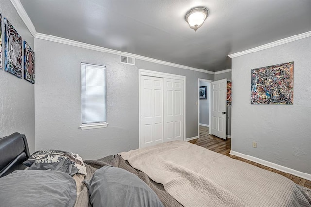 bedroom with hardwood / wood-style floors, a closet, and ornamental molding