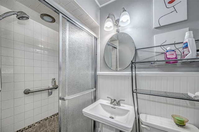 bathroom with sink, an enclosed shower, and toilet