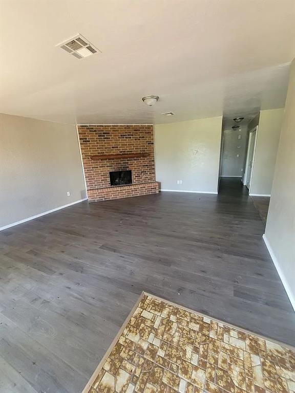 unfurnished living room with dark hardwood / wood-style flooring and a brick fireplace