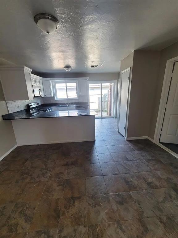 kitchen featuring white cabinets, electric range, decorative backsplash, and kitchen peninsula