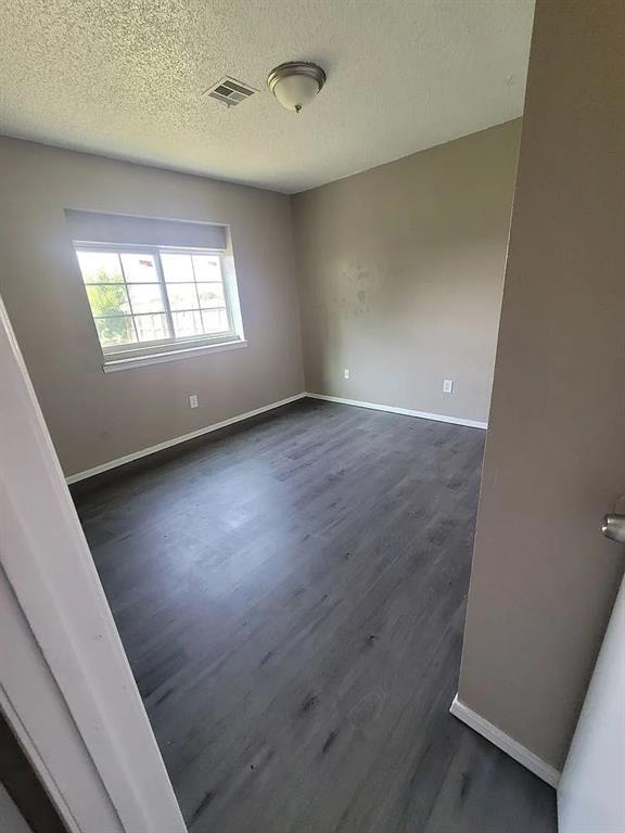 empty room with a textured ceiling and dark wood-type flooring