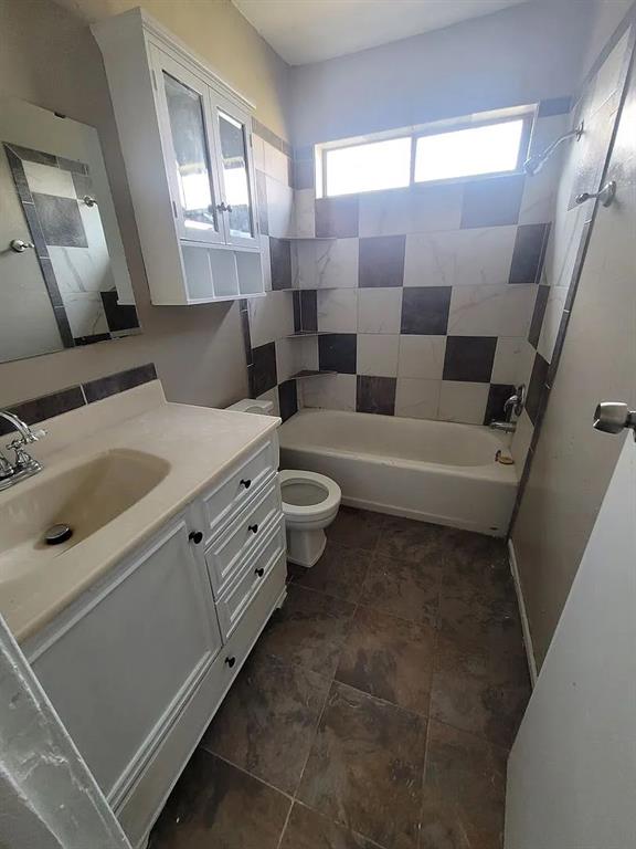 full bathroom featuring tiled shower / bath combo, toilet, and vanity