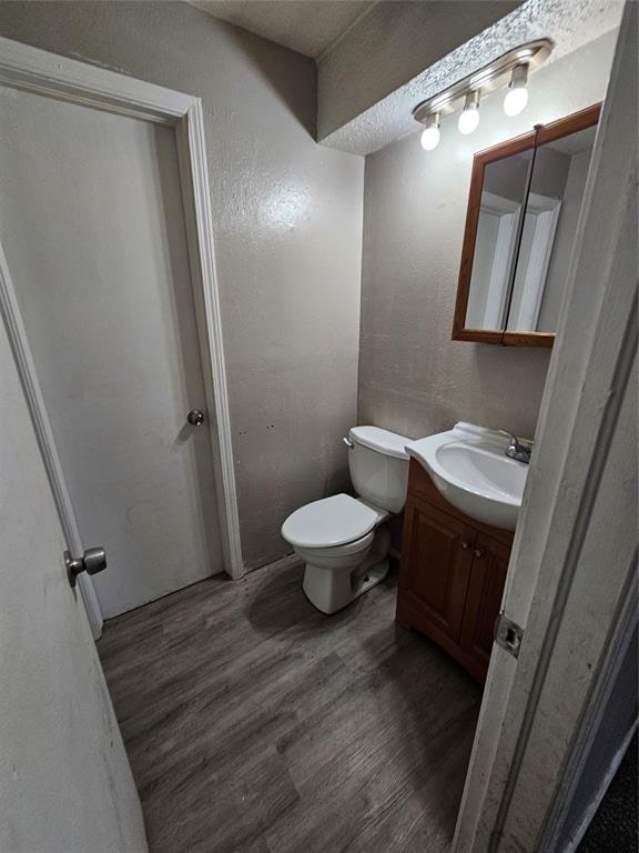 bathroom with hardwood / wood-style floors, vanity, a textured ceiling, and toilet