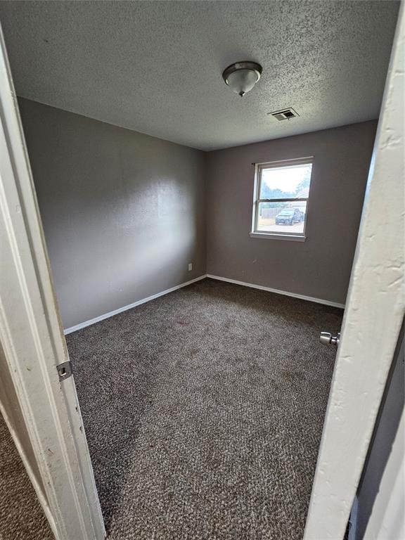 carpeted empty room featuring a textured ceiling