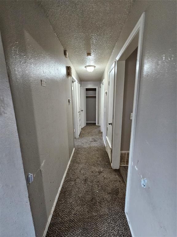 hall featuring carpet flooring and a textured ceiling